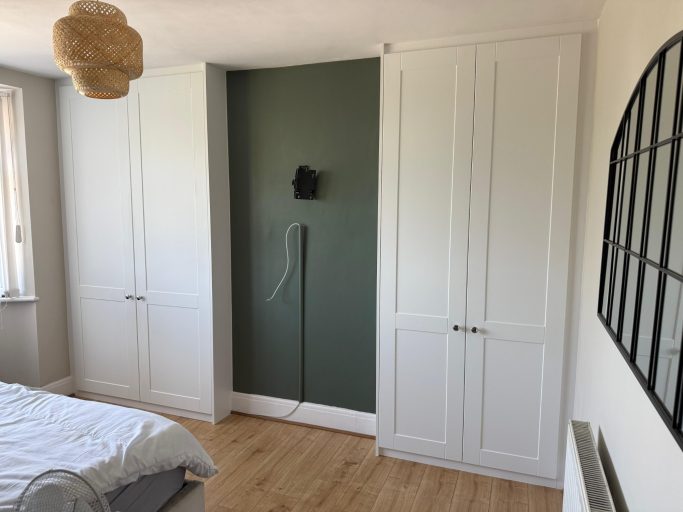 Bespoke fitted, custom made hinged wardrobes either side of chimney in Chatham, Kent. Vinyl wrapped doors with shaker style moulding.