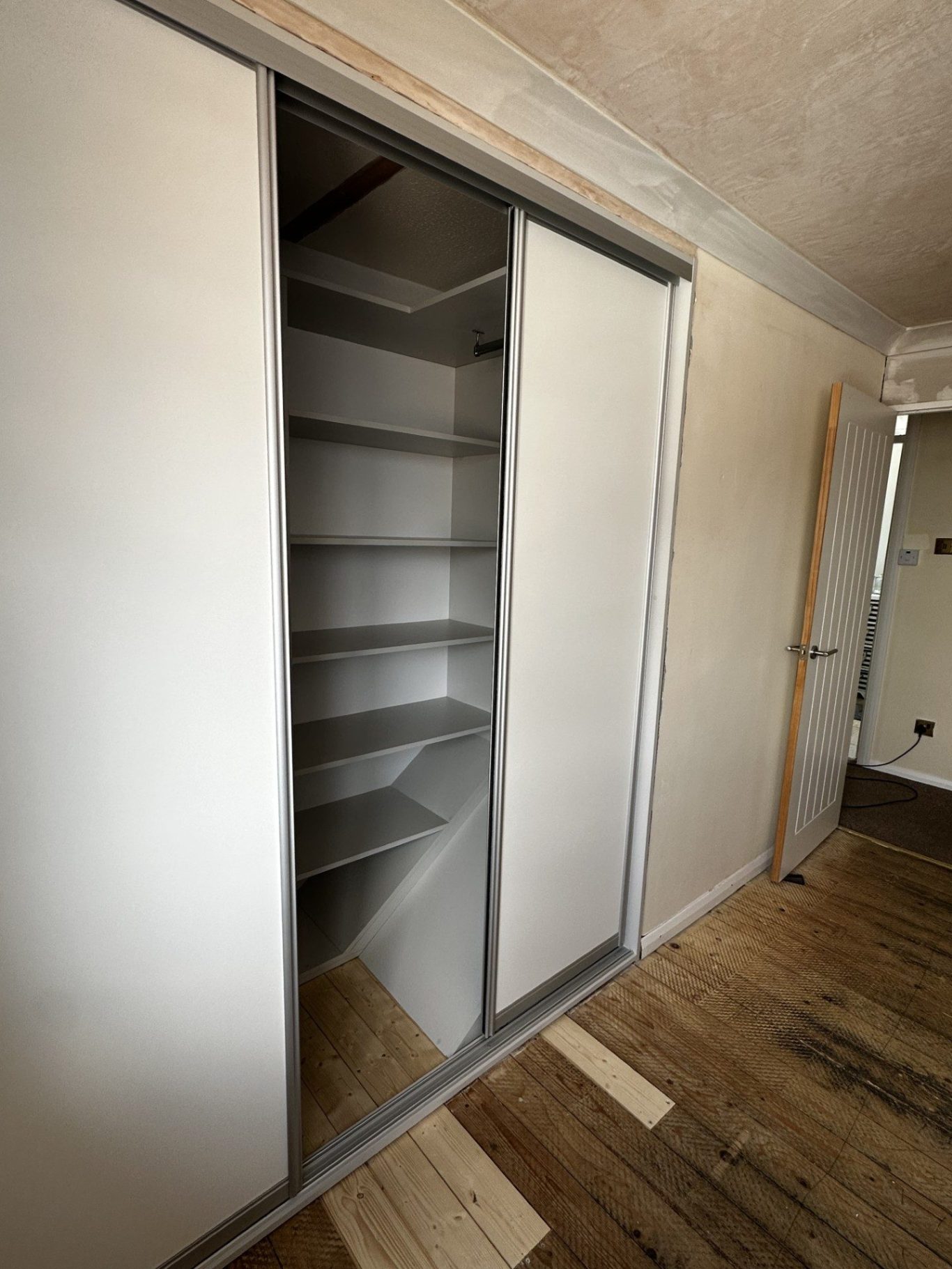custom made, bespoke sliding wardrobe over an angled stair box in Chatham, Kent